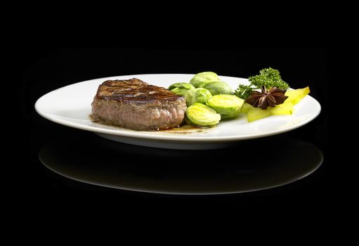 juicy filet mignon on plate with brussel sprout over black background