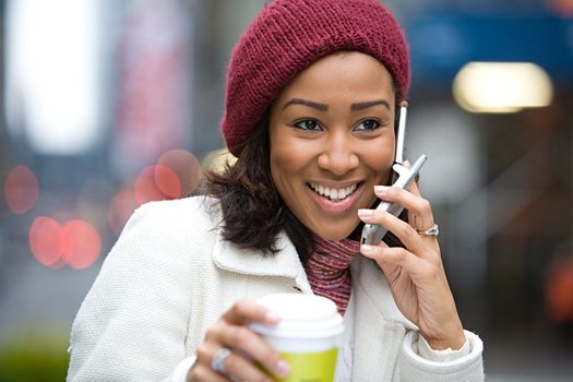 An attractive business woman talking on her cell phone along with a hot coffee.