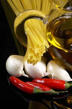 pasta garlic olive oil and red chili pepper ove black reflective surface