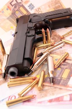 bullets, gun and money showing a dangerous side to life against a dark background
