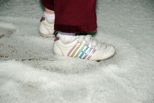 a child stepping on the ground after a winters hailstone shower