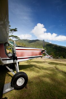 A small airplane on a grass mountain runway