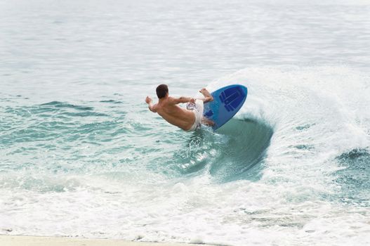 A lone male surfer balancing horizontally on the side of a wave