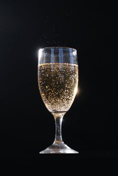 A glass of champagne with bubbles exceeding the rim.