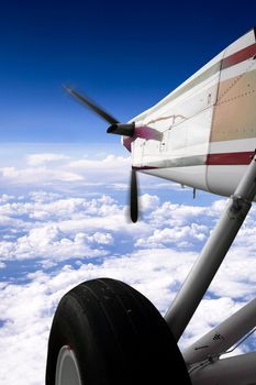 A small airplane in flight over clouds