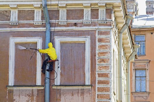 Cleaning service worker washing old building facade