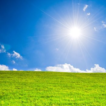 Sunbeams under a blue sky over green grass