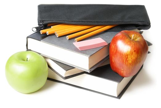 A stack of school books with an open pencil case and some apples.