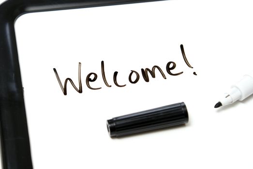 The word welcome is hand written in marker on an office white board.