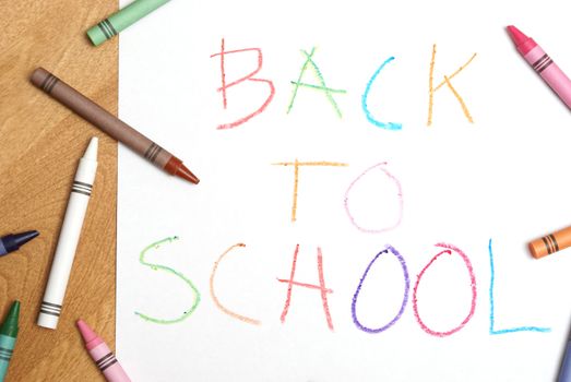 A childish back to school sign written in colorful crayons.