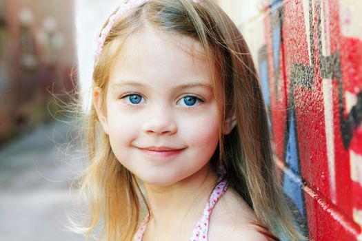 Little girl in an urban setting smiles at the camera.