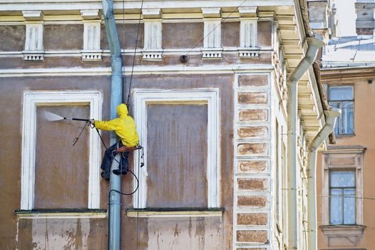 Cleaning service worker washing old building facade