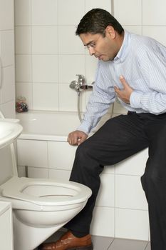 Photo of an adult male in his late thirties with stomach sickness about to vomit into his toilet.