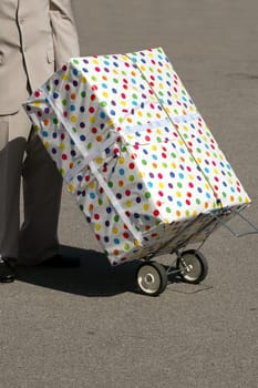 A man transportaing a very large present on a trolley.