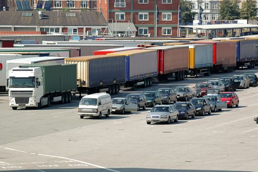 Cars and trucks. At the ferry many cars and trucks are waiting to get on.