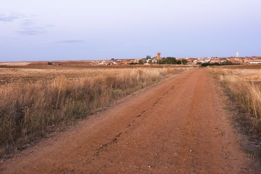 a rural road and a village at the background