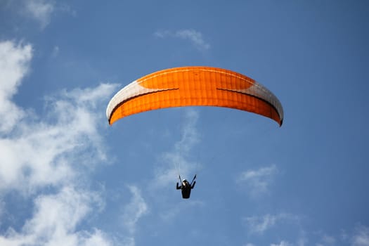 An orange paragliding in a blue sky