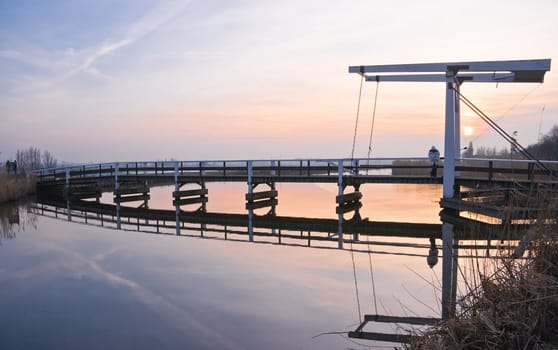 Old wooden lift-bridge in Dutch polderlandscape at sunset