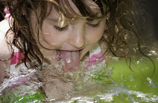 Girl playing outside with water on the summer