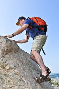 Middle aged man with backpack climbing a rock