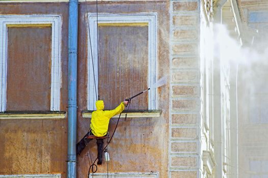 Cleaning service worker washing old building facade