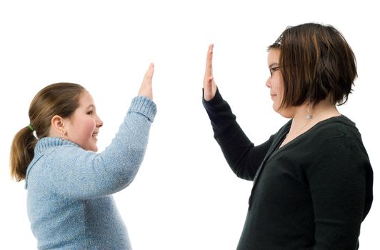 Two young girls giving each other a high five with their hands, isolated against a white background