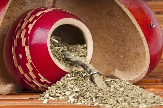 Close up of calabash cup with spill of yerba mate tea and straw. Use of Selective Focus.