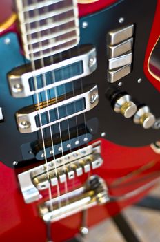 Red electric guitar close-up. Fragment, blur, selective focus on strings.