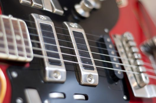 Red electric guitar close-up. Fragment, blur, selective focus on strings.