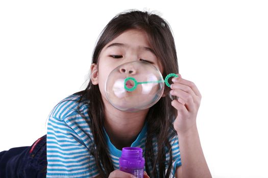 Small girl blowing bubbles lying on floor, part asian - Scandinavian descent