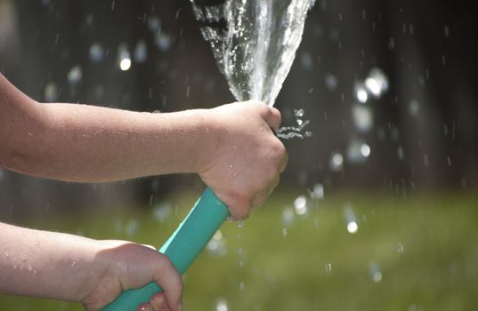 Girl playing outside with water on the summer