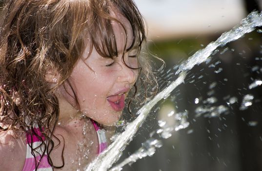 Girl playing outside with water on the summer