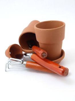 Several different sized terra cotta clay pots and gardening tools isolated on a white background.