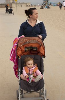 Woman pushing here child on beach walkway
