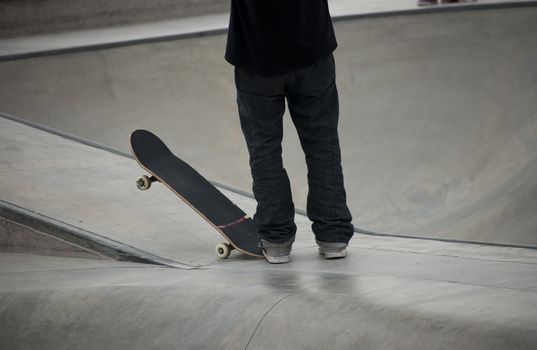 Teenager holding his skateboard at local skatepark