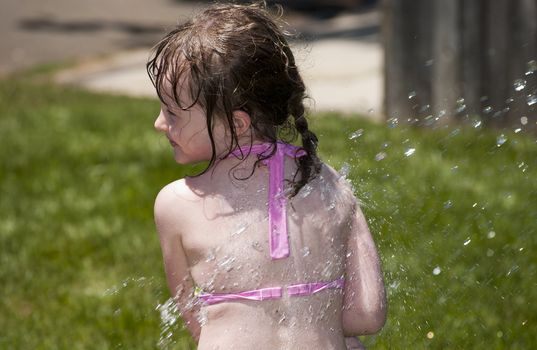 Girl playing outside with water on the summer