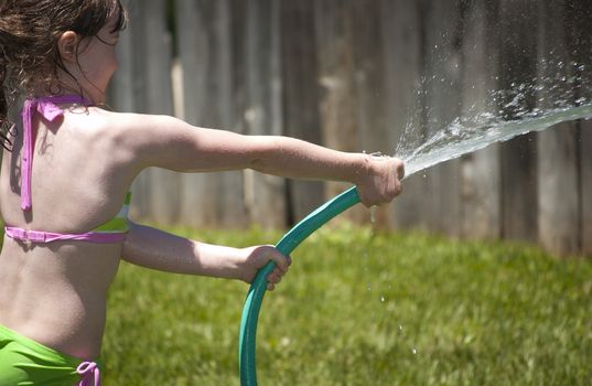 Girl playing outside with water on the summer