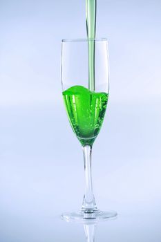 Green liquid drink being poured into wine glass