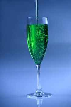 Green drink in glass against blue background