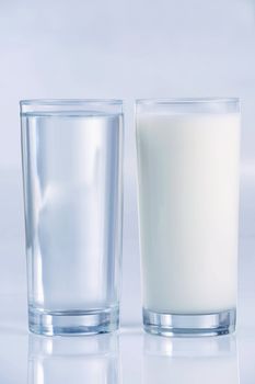Glass of water and milk, side by side, with blue tones,. Shallow DOF