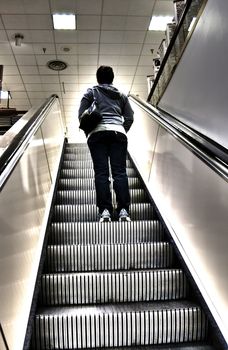 Going up surreal escalator in mall towards the light.