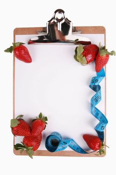 Healthy eating concept, fruit, strawberries. Tape measure and berries on clipboard