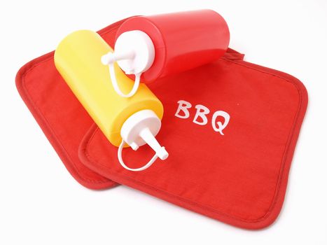 Ketchup and Mustard squeeze bottles laying on two red potholders.