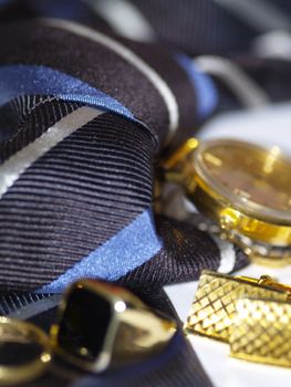 Detail photo of necktie, gold rings, cuff links and wristwatch, shallow dof
