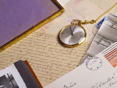 pocket watch over old postcards and photo album