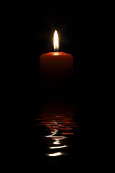 Burning candle reflecting in water