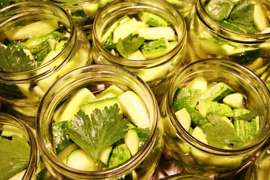 Glass jars filled with delicious green and tasty preserved cucumbers