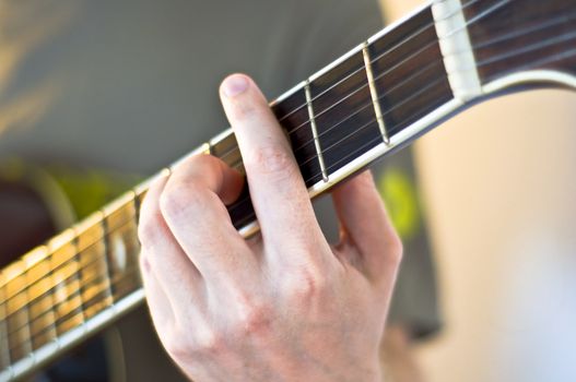 Hand holding a chord on the neck electric guitar. Close-up, selective focus on the musician's hand.