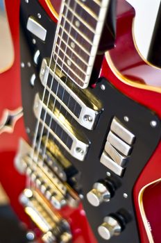 Red electric guitar close-up. Fragment, blur, selective focus on strings.