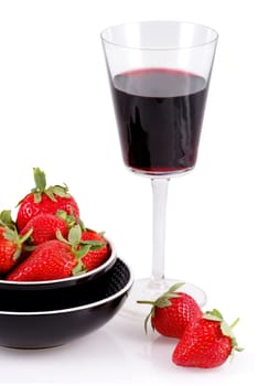 Glass of red wine and bowl with strawberries isolated on a white background.